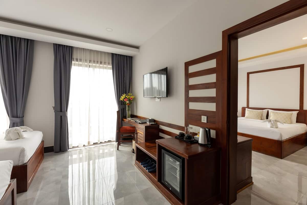 Una habitación de hotel con cama, escritorio con computadora, televisión y minibar.