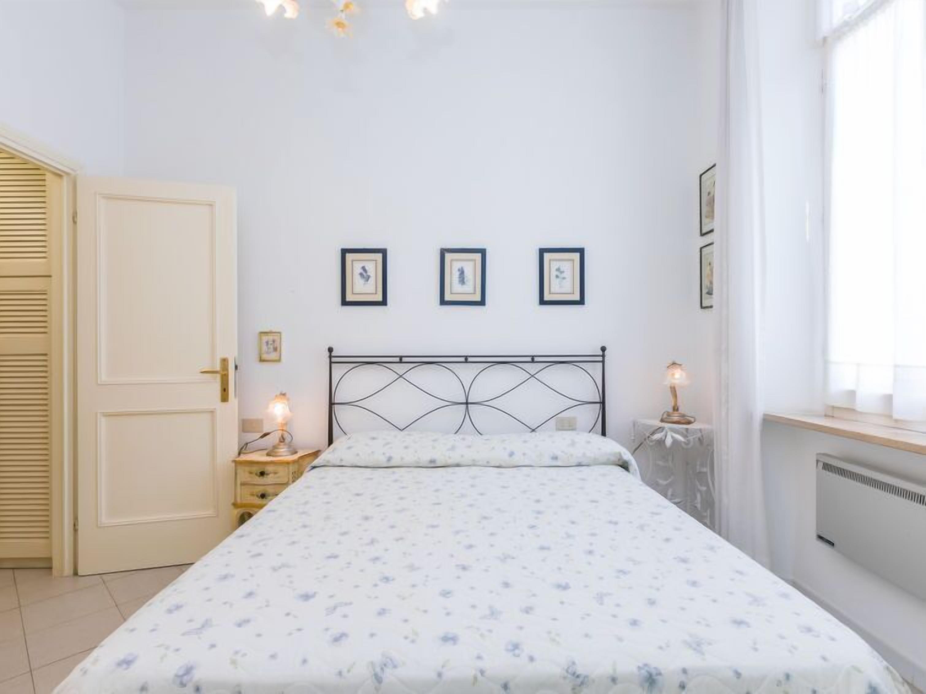 Une chambre à coucher avec un lit, une table de chevet, une commode et une fenêtre avec des rideaux.