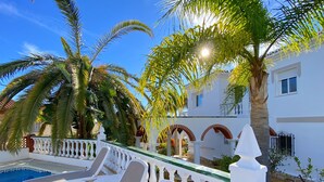 A pool area with white lounge chairs and a white balustrade.