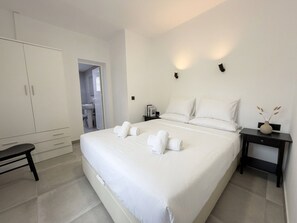 Une chambre d’hôtel avec un grand lit, une armoire, une table de chevet et une petite table.