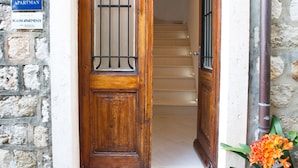 A wooden door with a metal gate, a staircase leading inside, and a sign indicating it's an apartment. - Casa Arancia (Dubrovnik)