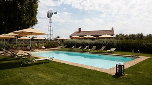 A swimming pool with lounge chairs and umbrellas, a windmill, and a building with a tiled roof. - Cozy family apartment for 6 people. (Lazio)