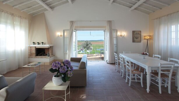 A spacious living room with a fireplace, a dining area, and a view of the outdoors. - Cozy family apartment for 6 people. (Lazio)