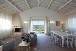 A spacious living room with a fireplace, a dining area, and a view of the outdoors. - Cozy family apartment for 6 people. (Lazio)
