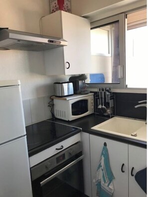 Uma cozinha compacta com geladeira, micro-ondas, fogão e pia.