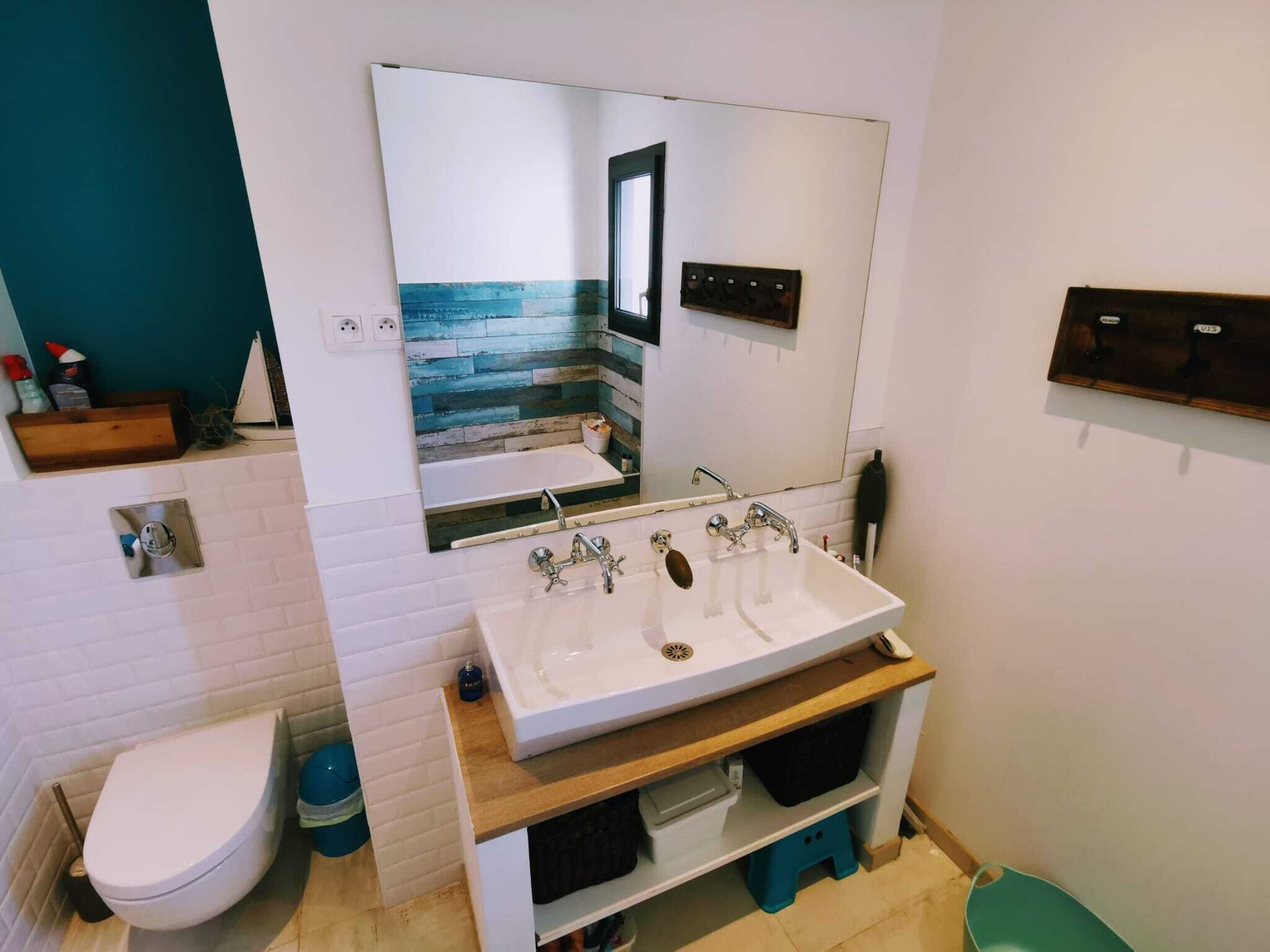 Een moderne badkamer met een witte wastafel, een spiegel en een toilet.