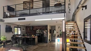 A spacious living area with a high ceiling, a kitchen in the background, and a staircase leading to an upper level. - Villa Avec Piscine en Campagne Aixoise au Cœur du Village Provencal de Ventabren (Ventabren)