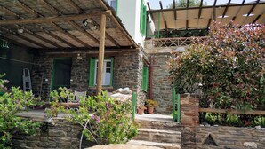 A stone building with a wooden pergola, outdoor seating, and potted plants.