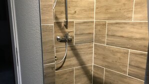 Een douchegedeelte met een wandbekleding van hout en een handdouche.