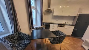 Une cuisine compacte comprenant une table et des chaises, une fenêtre avec des rideaux et un four encastré.