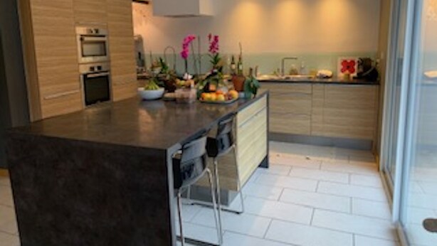 A modern kitchen with a central island, built-in oven, and a large window providing natural light. - Downtown Toulouse house with pool (Toulouse)