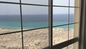 Una habitación con un ventanal grande con vistas a la playa y al océano.