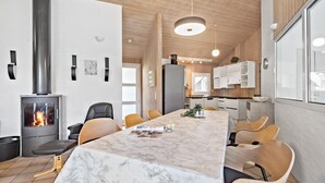 Une cuisine moderne dotée d’une cuisinière intégrée, de meubles en bois et d’une table à manger en marbre avec des chaises.