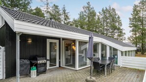 Un patio couvert équipé d’un barbecue, d’une table et de chaises d’extérieur.