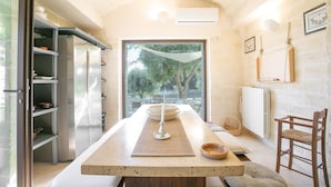 Une cuisine moderne dotée d’un grand îlot central, d’appareils électroménagers intégrés et offrant une vue sur l’extérieur.