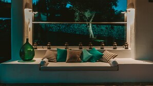 Un coin salon confortable avec un banc rembourré, un vase vert et des coussins à motifs.