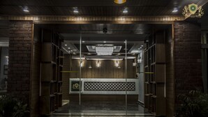 Zona de recepción con un mostrador de madera, una araña y un papel tapiz decorado.