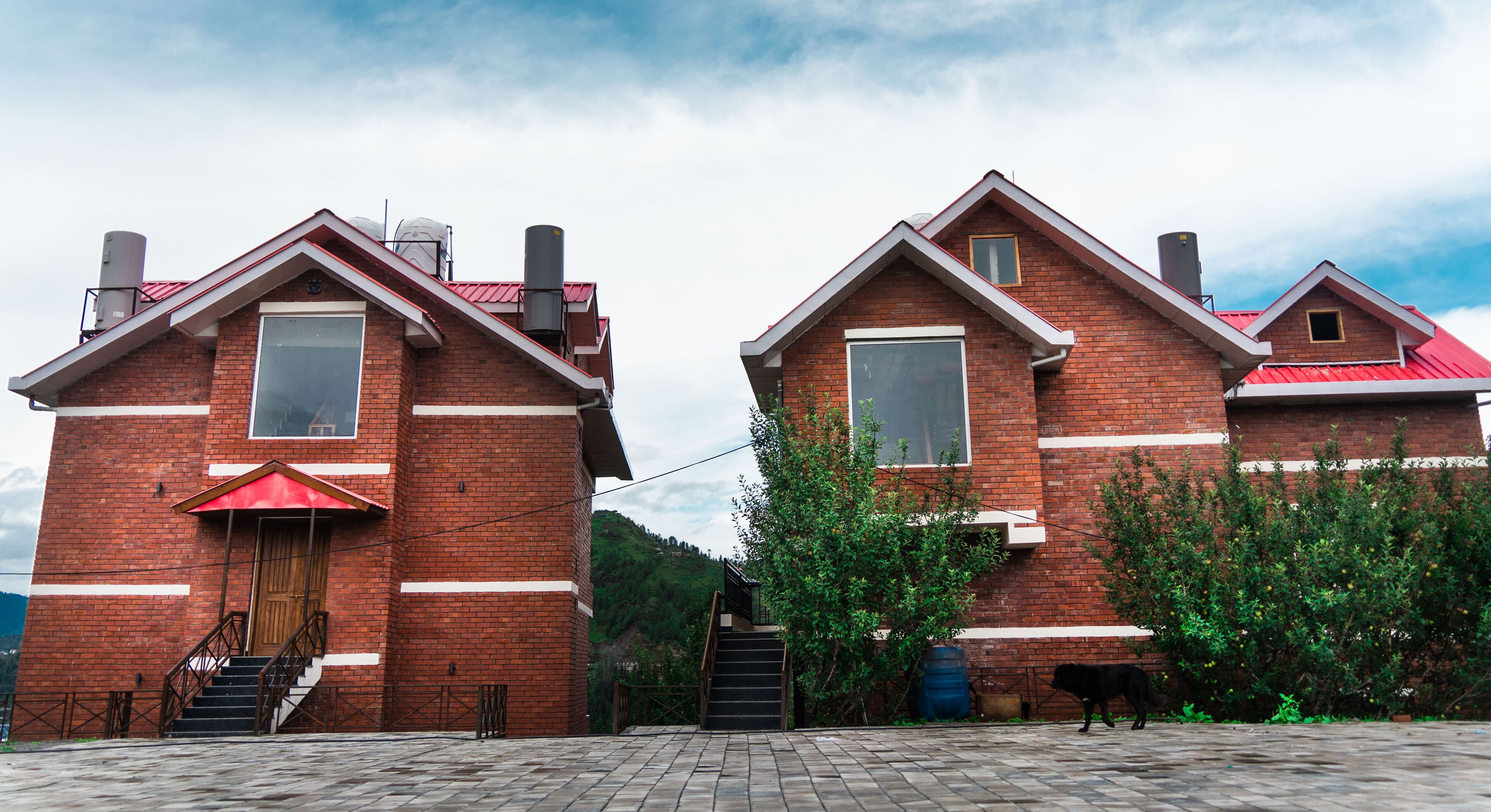 Two brick buildings with red roofs, a wooden door, and a red umbrella.