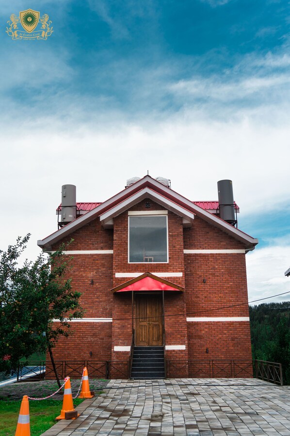 A brick building with a red roof, a large window, and a wooden door.
