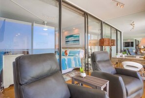 A modern hotel room with a large bed, two leather armchairs, a small table, and a desk with a lamp. - 11th fl. Oceanfront view plus parking and pool (San Diego)
