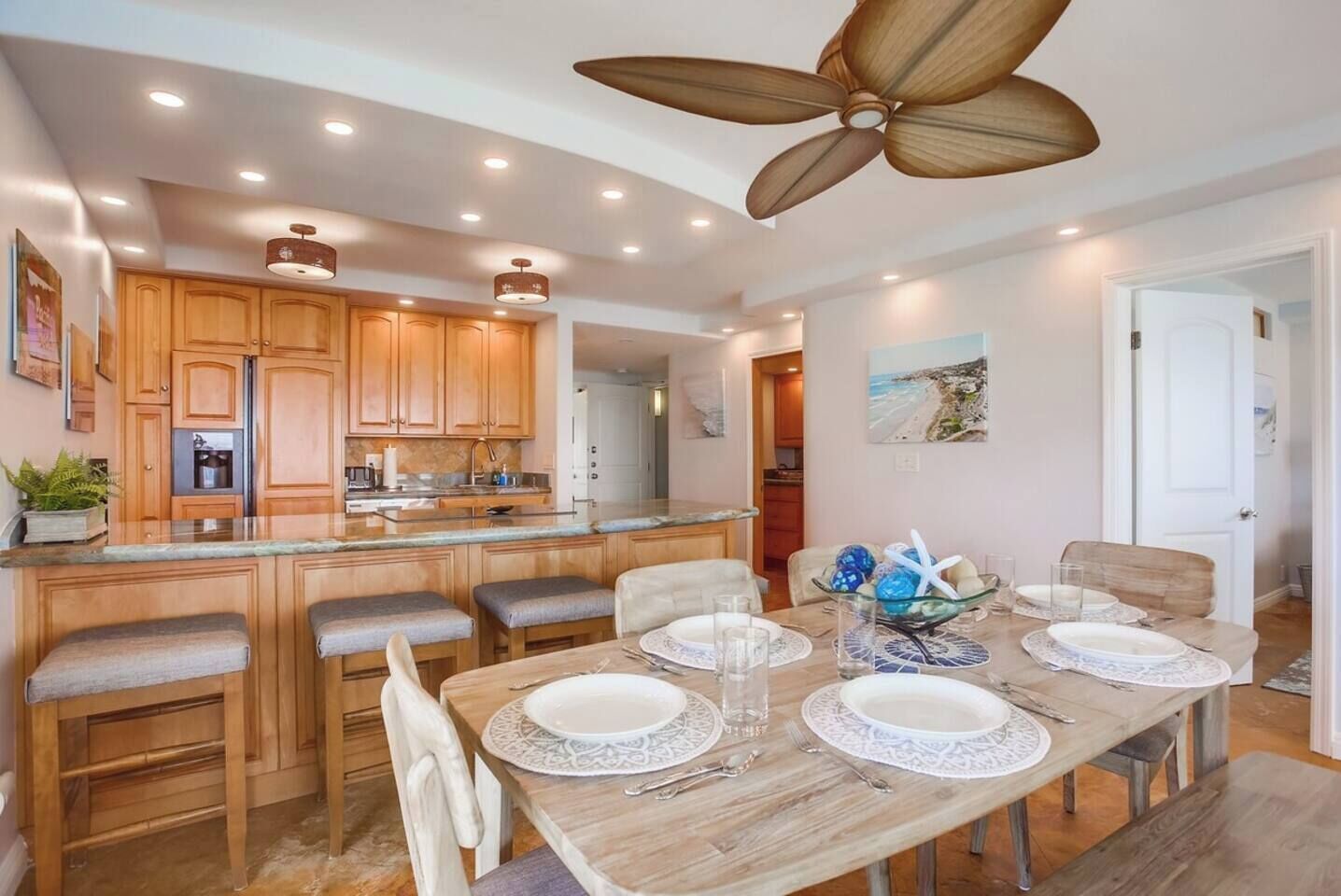 A modern kitchen with wooden cabinets, a central island, and a dining area with a large table set for six.