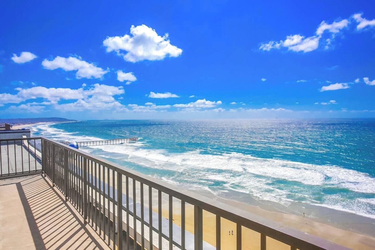 A coastal view with a wooden deck and railing overlooking the ocean.
