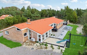 A two-story house with a red roof, a patio with outdoor furniture, and a slide. - Gorgeous home in Blåvand with sauna (Blåvand)