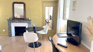 A living room with a fireplace, a round table with chairs, a TV, and a remote control. - Apartment Bossoreil 110m2 - Hyper center Angers (Angers)