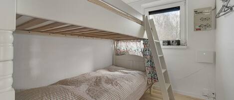 A bunk bed room with a window, wooden floor, and a ladder.