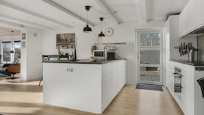 A modern kitchen with a central island, a dining area with a chair, and a large window. - Lovely home in Hurup Thy with sauna (Hurup Thy)