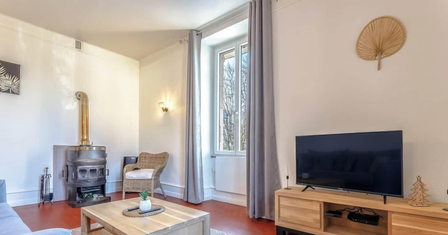 Una sala moderna con estufa de leña, televisor y un rincón de estar acogedor.