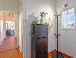 A hallway with a dark-colored cabinet, a coat rack, and a window with a view of a building. - La Savoyarde - T2 apartment close to the lake. (Menthon-Saint-Bernard)