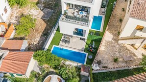 Een modern huis met twee verdiepingen, een zwembad, terras en tuin.