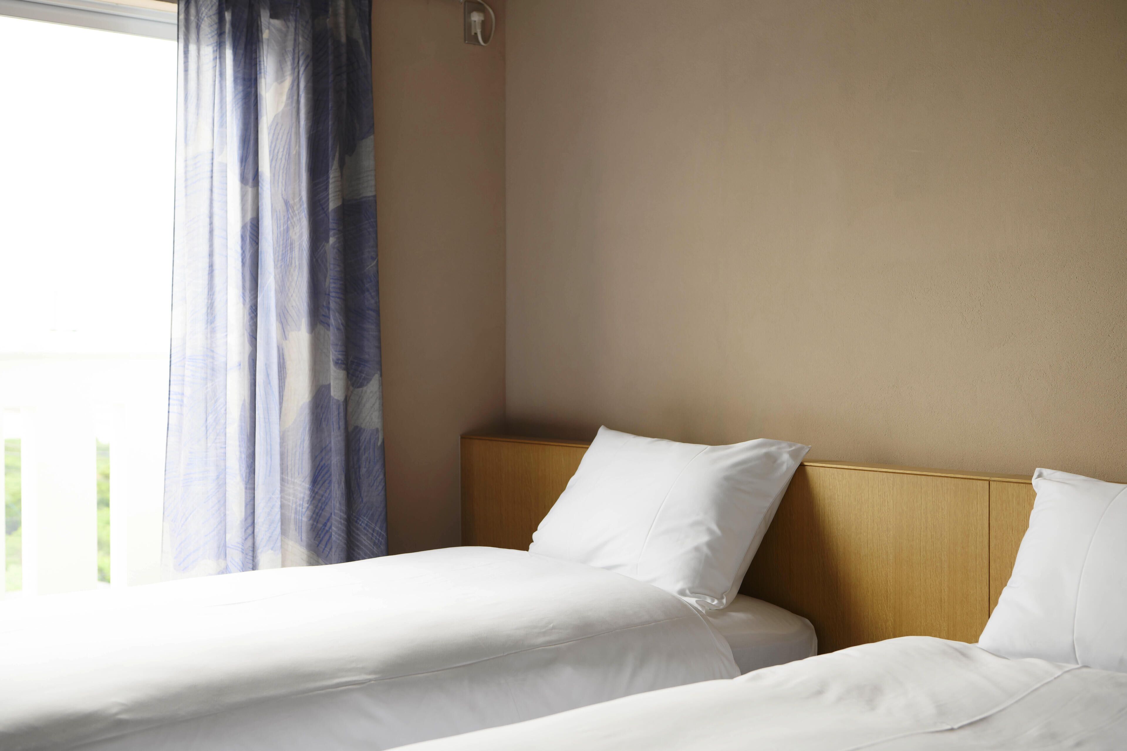 A hotel room with two beds, a wooden headboard, and a window with curtains.