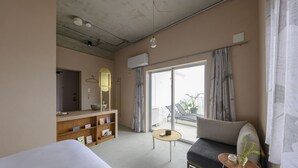 A hotel room with a bed, a sofa, a small table, a mirror, and a balcony with a view. - Meguru Ishigaki (Ishigaki)