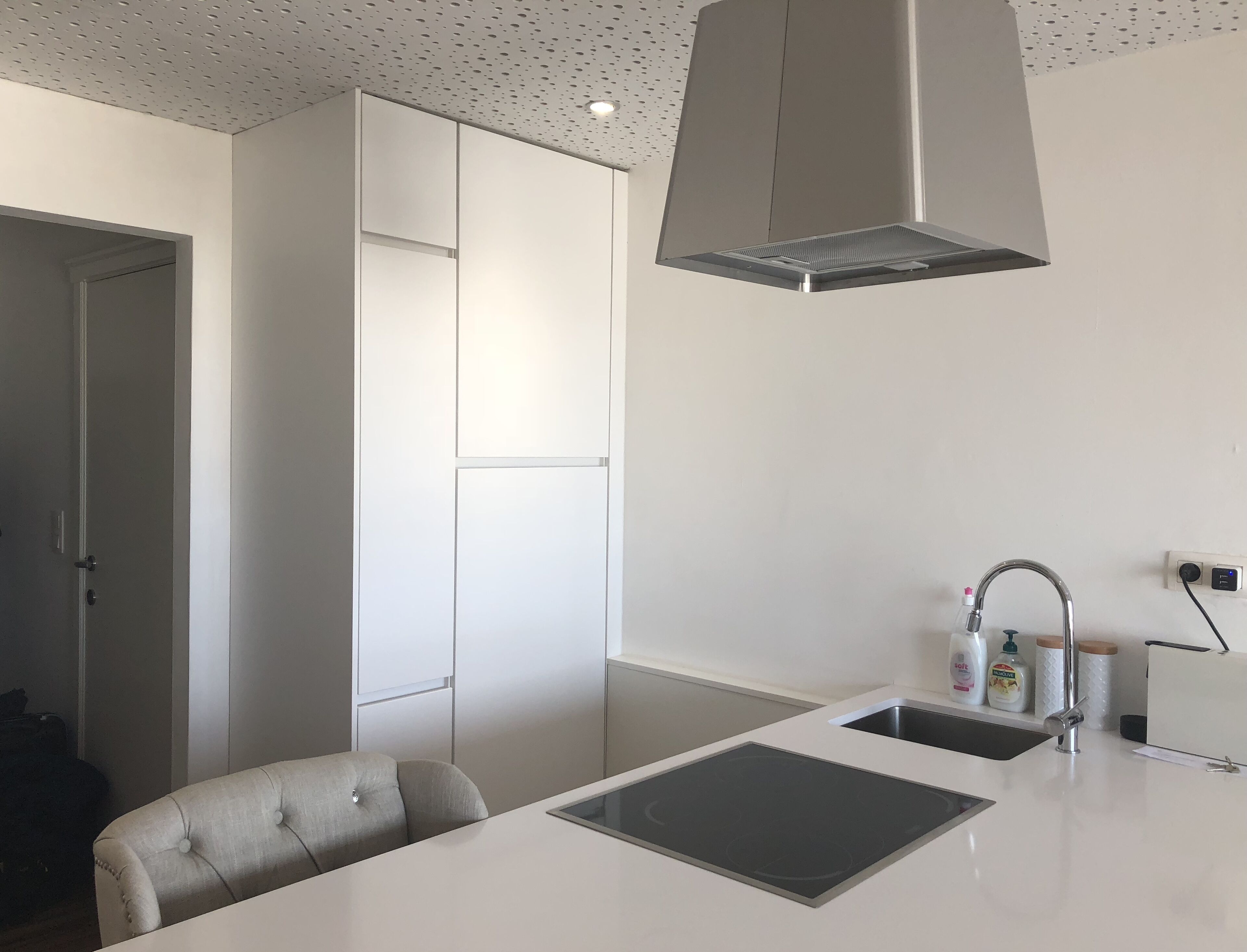 Una cocina moderna con estufa integrada, un lavamanos y una lámpara colgante.