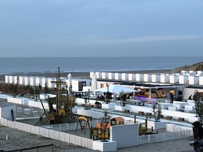 A beachside hotel with white buildings, outdoor seating, and a playground.