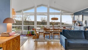 A spacious living room with a large window, wooden furniture, and a blue sofa. - Amazing home in Vejby with WiFi (Vejby)