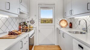A compact kitchen with white cabinets, a wooden countertop, a stainless steel sink, and a window with a vineyard view. - Amazing home in Vejby with WiFi (Vejby)
