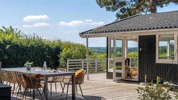 A wooden deck with a table and chairs, a covered seating area, and a view of the surrounding landscape. - Amazing home in Vejby with WiFi (Vejby)