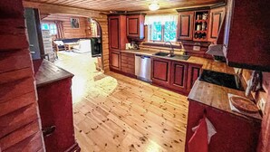A cabin interior with wooden floors, a kitchen with a sink and cabinets, and a dining area with a table and chairs. - 4 bedroom beautiful home in Sälen (Sälen)