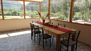 Un comedor con una gran mesa, sillas y vistas a un paisaje montañoso a través de amplios ventanales.