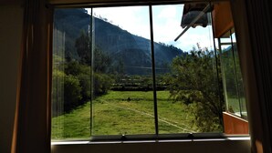 Una habitación con un ventanal amplio que ofrece vistas a un campo verde y montañas.