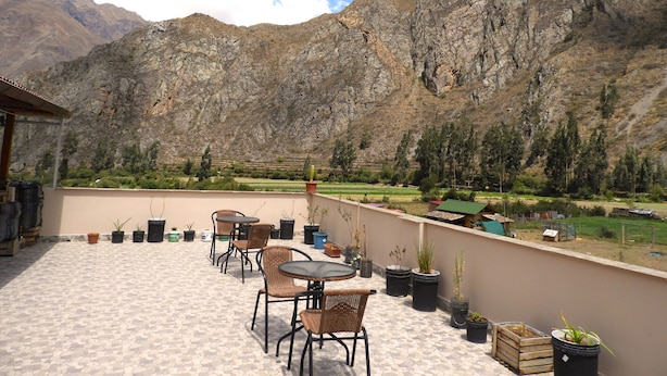 Una terraza con mesas al aire libre y macetas con plantas, con vistas a un paisaje montañoso.