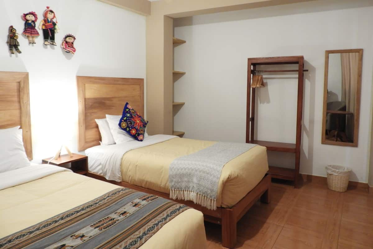 A bedroom with two beds, wooden headboards, a wardrobe, a mirror, and a wall with decorative items.