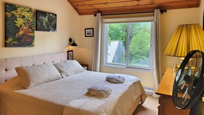 Una camera da letto con un letto, una finestra, una lampada e un ventilatore.