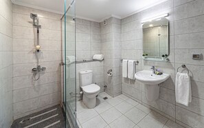 Moderni kylpyhuone, jossa on lasiseinällä varustettu suihku, wc, pesuallas ja peili.