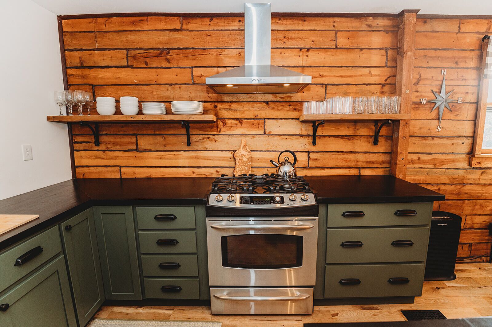 Une cuisine équipée d’une cuisinière, d’un four et de lambris en bois.