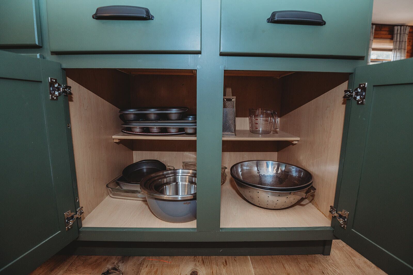 A kitchen cabinet with two shelves, each holding various kitchenware items.