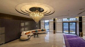 Eine moderne Lobby mit einer Chandelier, einer Couch und einem violetten Teppich.